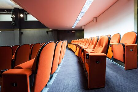 in an small theater there are orange seats in a rowの写真素材