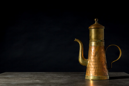 an old copper coffeepot on a black backgroundの写真素材
