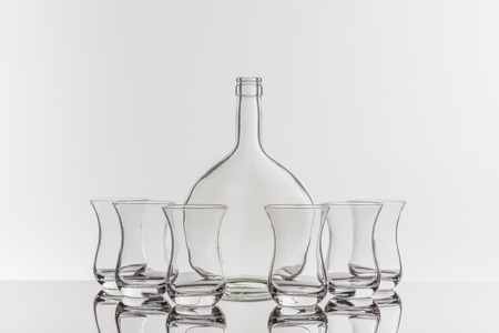 On a reflective tile is an empty transparent bottle and glassの写真素材