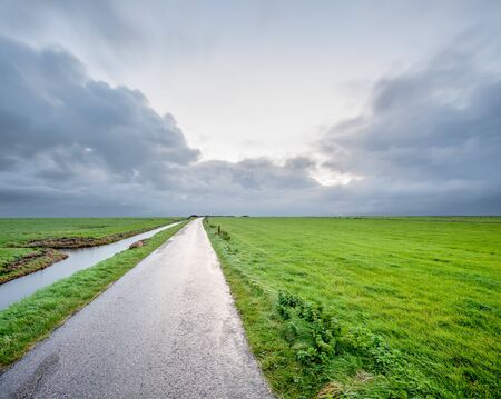 In the north of the Netherlands, this hiking trail is next to the meadow with Stratus Clouds on a...