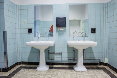 in an public restroom hangs on an wall of an white sinkの写真素材