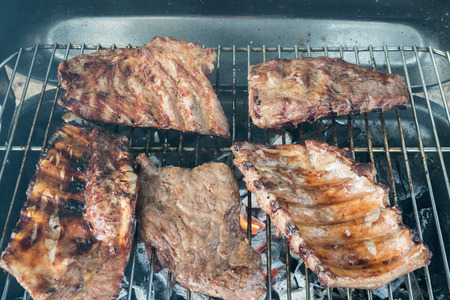 On charcoal barbecue there are ribs and a tasty steakの写真素材