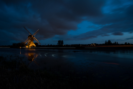 these beautiful windmills in Kinderdijk are illuminated with white light at the blue hourの写真素材
