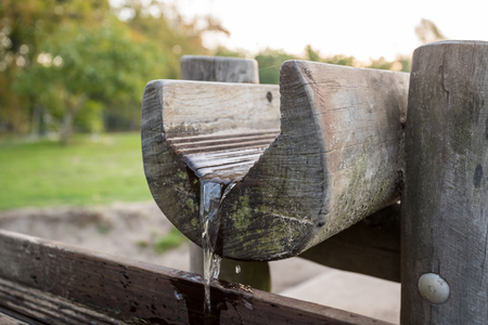 in a park there is a wooden waterfall with a water pumpの写真素材