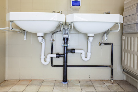 in an public restroom hangs on an wall two white sinksの写真素材