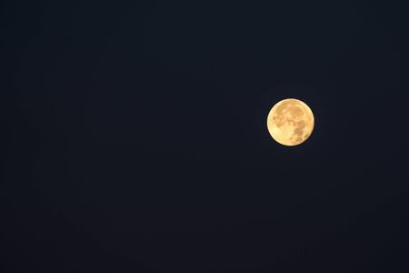 on a beautiful morning, the start of a sunny day, the full moon shines in the skyの写真素材