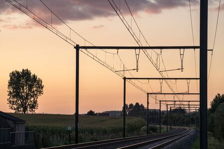 This track with electrical lines above runs in the distance of the landscapeの写真素材