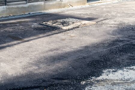 New asphalt with a large iron manhole cover of the cesspit