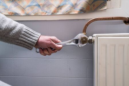 in the bathroom, the plumber is installing the thermostatic radiator valveの写真素材