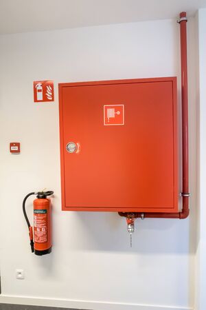 an fire hose hanging on the wall in an corridorの写真素材