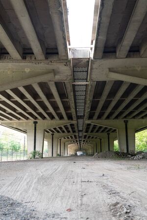 this dusty earth runs away under a viaduck of a motorway