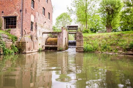 In the countryside there is an old watermill on the waterの写真素材