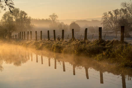 On a November morning in autumn this fog hangs over the river along the meadow and the trees.の写真素材