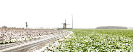 During snowing at the Vinke windmill (Vinkemole) with a gray sky and snow on the fieldの写真素材