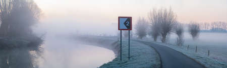Early on a frosty morning with fog, this bike and footpath runs along the riverの写真素材