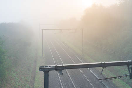 On a Foggy morning on the track with overhead lines and a rising sunの写真素材
