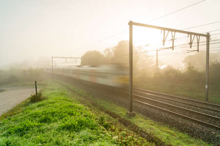 hangs a thick fog along the road and railの写真素材