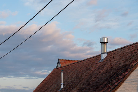 on a tile roof there is a Inox Chimney tube on a sunny dayの写真素材