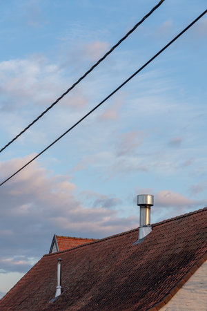 on a tile roof there is a Inox Chimney tube on a sunny day