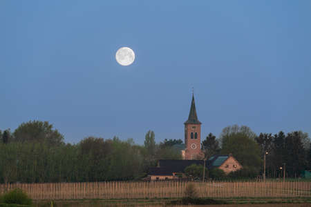 Early in the morning this beautiful Moon is next to a churchの写真素材