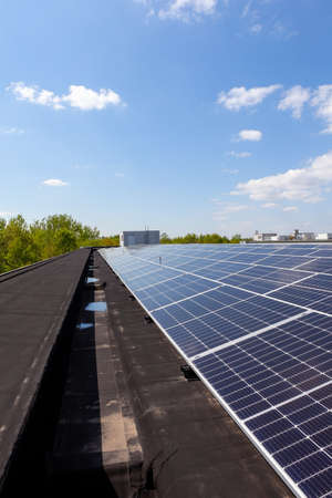on an building in an residential area, there are solar panels on the roof on sunny dayの写真素材