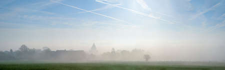 Early in the morning whit a lot of fog ,you see a roof of an churchの写真素材