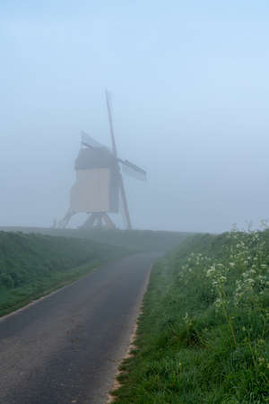 Early in the morning there is a beautiful windmill in the mist whit the sun rising in the skyの写真素材