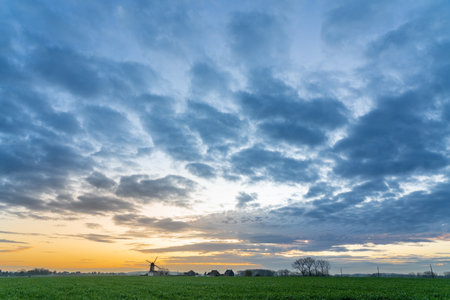 Early in the morning there is a beautiful windmill whit the sun rising in the skyの写真素材