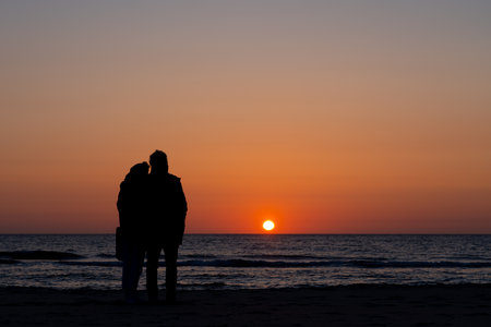 this couple in love is enjoying the sunset over the sea
