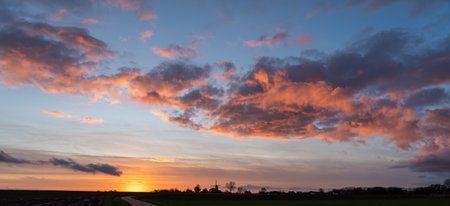 On a beautiful evening with these beautiful colored clouds above a windmillの写真素材