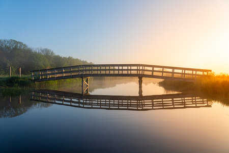 in the early morning this footbridge across the river with the rising sun with very beautiful colorsの写真素材
