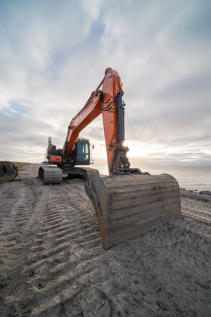 By the sea, an excavator is paving the sea sand.の写真素材