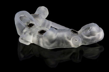 specially made surgical template for dental implantation of the lower jaw on a black background