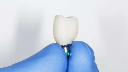 zirconium crown in the hand of an orthopedist on a white backgroundの写真素材