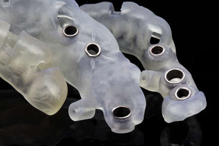 various titanium sleeves in dental templates on a black background