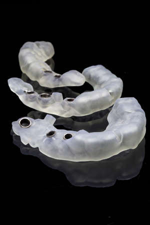 excellent composition of three dental templates for implantation, laid out on a black background