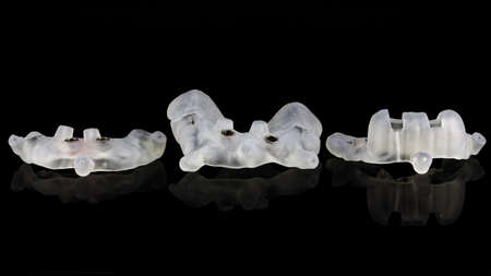 dental photo of three surgical templates for large implantation surgery on black glass with...