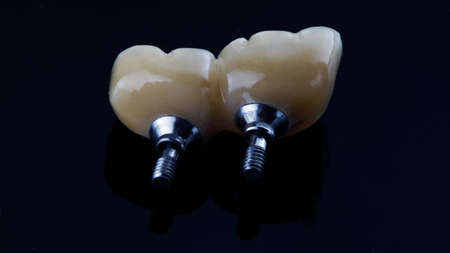 ceramic crowns and orthopedic prosthetics in the form of fixation screws, filmed on a black...