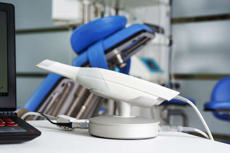 modern intraoral dental scanner connected to a laptop on the background of dental surgery