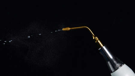 dental gilded nozzle with jet of water, shot against a black backgroundの写真素材