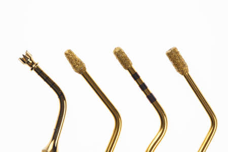 four dental attachments for implantation and sinus lifting, gold-colored cutters on a white backgroundの写真素材