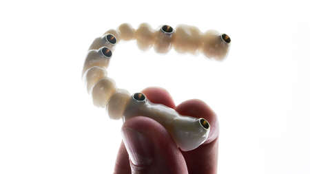 dentist holds in his hand a prosthesis made of quality materials on a white background