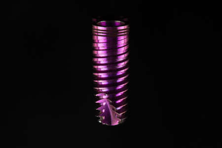 dental implant replica for training purposes and demonstrations on a black background