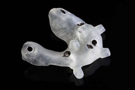 Dental template for the installation of six implants removed at an angle on a black background