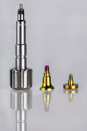 perfect composition of a prosthetic screwdriver, dental abutment and a gold-colored plug, on a light...