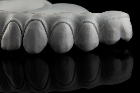 creative dental photo with a view of the chewing teeth of a zircon prosthesis on a black background with reflectionの写真素材