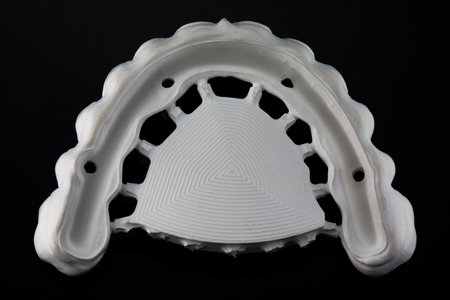 inverted dental prosthesis made of zircon with space for a titanium beam, top view on a black...