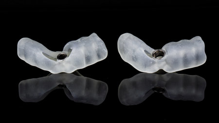 two surgical dental templates for installing one dental implant on black glass with reflection