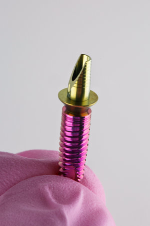 An implant held by a hand in a glove on a white background.の写真素材
