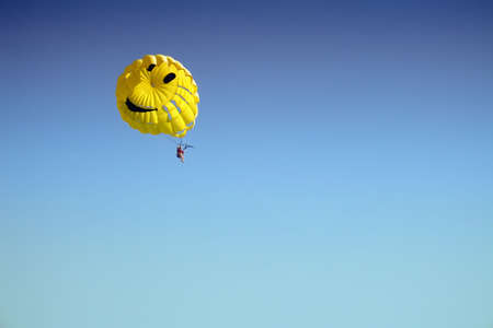 Yellow parachute high in the blue sky    の写真素材